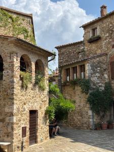 Dos personas sentadas afuera de un antiguo edificio de piedra. en Maremma Castle Apartament, en Montemerano