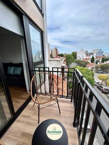 a chair on a balcony with a view of a city at HOMEY Departamentos in Mar del Plata
