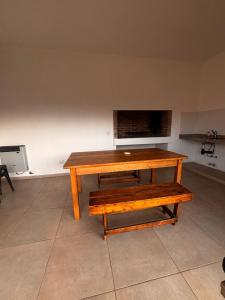 una mesa de madera y un banco en una habitación en La Arequera, en San Antonio de Areco