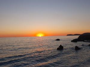 a sunset over the ocean with rocks in the water at Room zero of Sea in Borsh