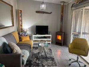 a living room with a couch and a fire place at Lente Beach Cottage, Fleur Park, Gordon's Bay in Gordonʼs Bay