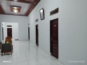 a hallway with black doors and white walls at Wisma sane in Teratakairhitam