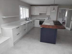 a kitchen with white cabinets and a blue island at The Barn in Clonmel