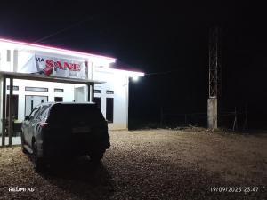a car parked in front of a gas station at night at Wisma sane in Teratakairhitam