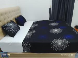 a bed with a black and white comforter and pillows at Wisma sane in Teratakairhitam