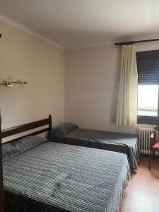 a bedroom with two beds and a window at Hostal Esplai in Viladamat