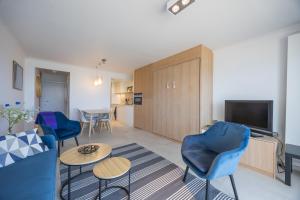 a living room with a blue couch and chairs at Aldis - beachfront in Ostend