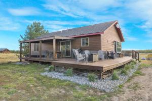 una baita di tronchi con terrazza e sedie. di Hottub Mountain Views Atv Trails Trailer Parking a Island Park