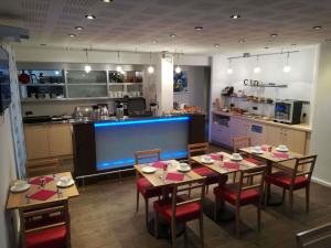 a dining room with a table and a kitchen at Hôtel Mercure Vittel in Vittel