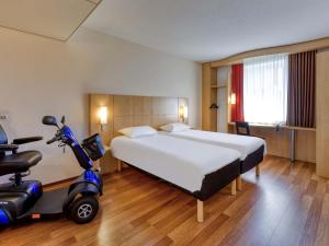 a hotel room with a bed and a scooter in it at ibis Konstanz in Konstanz