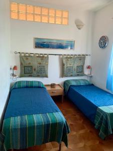 two beds in a room with blue and green sheets at Casa MìMì in La Maddalena