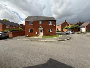 Una casa de ladrillos rojos en una calle con coches aparcados. en Aylesbury, en Buckinghamshire