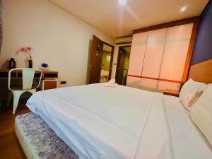 a bedroom with a large white bed and a chair at vortex KLCC YOUR HOME in Kuala Lumpur