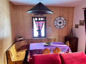 una stanza con un tavolo e un orologio sul muro di Spazioso appartamento vicino al centro a Bormio