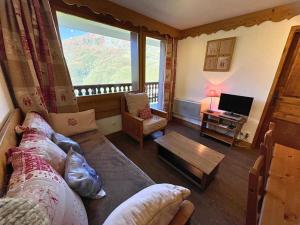 a living room with a couch and a large window at Appartement aux Menuires avec cuisine équipée, balcon et animaux admis - FR-1-452-15 in Les Menuires