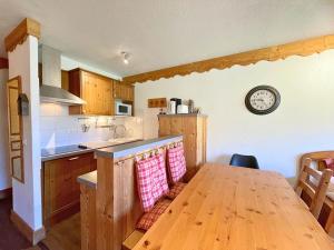 a kitchen with a wooden table and a clock on the wall at Appartement aux Menuires avec cuisine équipée, balcon et animaux admis - FR-1-452-15 in Les Menuires