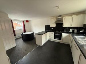 Una cocina con gabinetes blancos y una encimera negra. en Aylesbury, en Buckinghamshire 6 fotos más