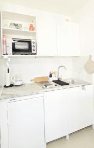 a white kitchen with a microwave and a sink at Bestlage - Gemütliche Wohnung in der Mainzer City in Mainz