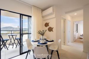 a dining room with a table and chairs and a balcony at Estadia completa com piscina e academia a 400m da Praia da Armação - SKL in Penha