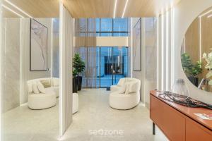 a lobby with two white chairs and a desk at Apartamentos Bem Equipados a 100 m da Praia - EVR in Perequê