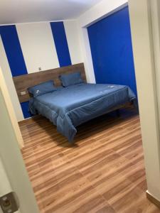 a bedroom with a bed with blue walls and a wooden floor at Hotel Huancayo - El Toro Wanka in San Antonio
