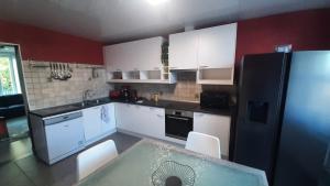 a kitchen with white cabinets and a black refrigerator at Le duo virtonnais - appartement 4 personnes au coeur de la gaume in Virton