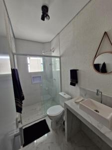a bathroom with a toilet and a shower and a sink at Pousada Praia do Guaiuba in Guarujá