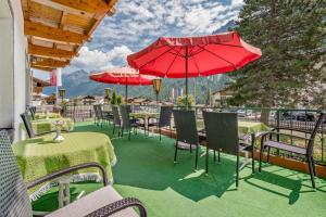 Pension Almrausch في نيوستيفت ام ستوبايتال: فناء به طاولات وكراسي ومظلات حمراء
