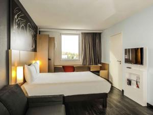 a hotel room with a large bed and a couch at Ibis Saint-Genis-Pouilly Genève in Saint-Genis-Pouilly