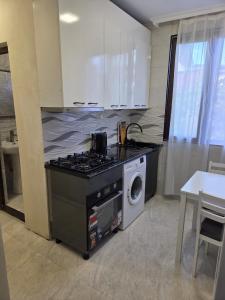 une cuisine avec une cuisinière et une machine à laver dans l'établissement Family house in Kobuleti, à Kobuleti