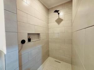 a bathroom with a shower with white tiles at East Park Inn in Polokwane