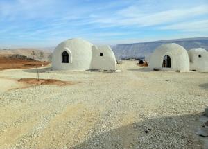 a group of white domed buildings in the desert at Tootya camp in Al Mathlūthah
