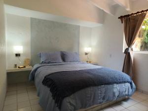 a bedroom with a bed with blue sheets and a window at Portal Azahualco Bungalow close to the mountain in Tepoztlán