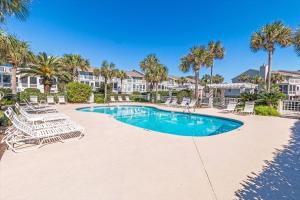 a swimming pool with lounge chairs and palm trees at Beach Club Villa 30 - Coastal Oceanfront! Pool! Walkout! in Isle of Palms