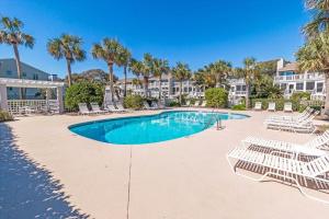 a swimming pool with lounge chairs and palm trees at Beach Club Villa 30 - Coastal Oceanfront! Pool! Walkout! in Isle of Palms