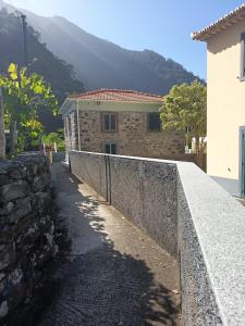une maison avec un mur en pierre à côté d'un bâtiment dans l'établissement Pousada Teixeira 11A, à São Vicente