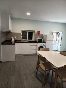 une cuisine avec des armoires blanches et une table et des chaises dans l'établissement Pousada Teixeira 11A, à São Vicente