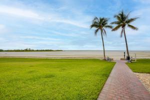 a brick walkway next to a beach with two palm trees at 4 Mi to Lovers Key SP Modern Condo with Ocean Views in Fort Myers Beach
