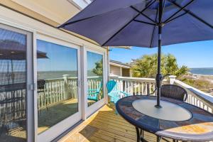 einen Tisch mit Sonnenschirm auf einem Balkon mit Meerblick in der Unterkunft Seagrove Villa 11C - Oceanfront View! Center of Resort! in Isle of Palms