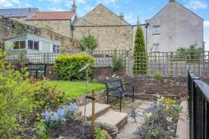 een tuin met twee bankjes voor een hek bij Bondgate House in Alnwick