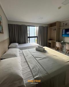 ein Hotelzimmer mit drei Betten und einem Fernseher in der Unterkunft Flats Move - By EasyHost in João Pessoa