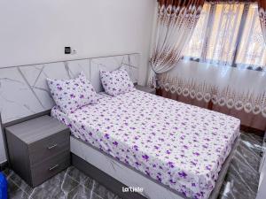 una piccola camera da letto con letto con lenzuola e cuscini rosa di Magnifique Mini-Villa Ouagadougou! a Ouagadougou