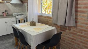 a kitchen with a table with chairs and a brick wall at Cabañas Las Rositas in Villa de Las Rosas