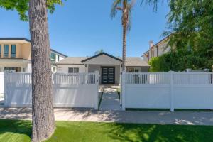 a white fence in front of a house at Modern Encino Retreat with pool, lush yard and comfort in Encino