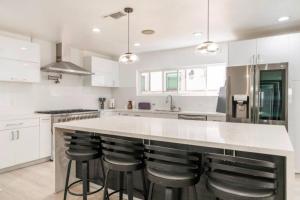 a kitchen with white cabinets and a large island with bar stools at Modern Encino Retreat with pool, lush yard and comfort in Encino