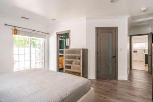 a bedroom with a bed and a dresser and a door at Modern Encino Retreat with pool, lush yard and comfort in Encino +42 photos