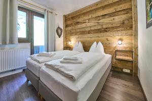 una camera con 2 letti e una parete in legno di Apartments Enzian a Rauris