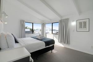 een witte slaapkamer met een bed en een raam bij Parnell Home with Pool, Parking and Rangitoto View in Auckland +26 foto's