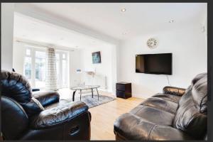 South Ruislip StationにあるFamily Friendly 3BR Haven in Northolt with Parkingのリビングルーム(革張りのソファ2台、薄型テレビ付)