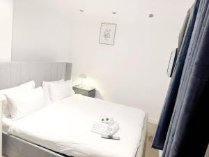 a bedroom with a white bed with a book on it at Family Friendly 3BR Haven in Northolt with Parking in South Ruislip Station